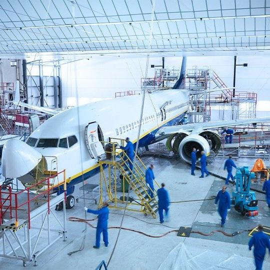 Team of airplane technicians working on a commercial plane inside a hanger